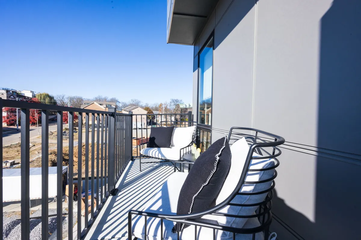 A tranquil balcony scene with stylish outdoor chairs, railing, and a clear view of the surrounding area. The setting is ideal for relaxing with a book, enjoying morning coffee, or watching the sunset—activities families might cherish after a busy day out.