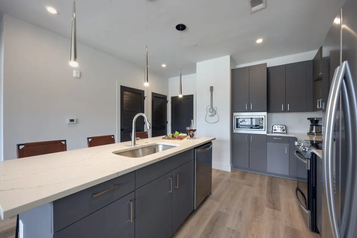 A welcoming kitchen with a prominent island, stainless steel appliances, and a guitar on the wall—bringing a clear nod to Nashville's musical heritage. The layout is open and perfect for socializing, cooking, or brunching together.