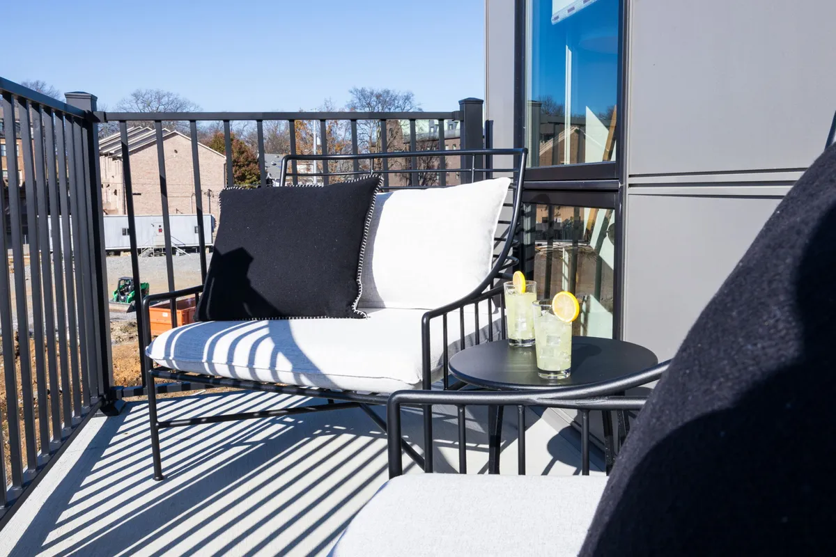 A cozy exterior lounge setup with a comfortable chair and a small table holding refreshing drinks. The tranquil mood invites relaxation and casual gatherings, ideal for downtime between urban adventures or enjoying city views.