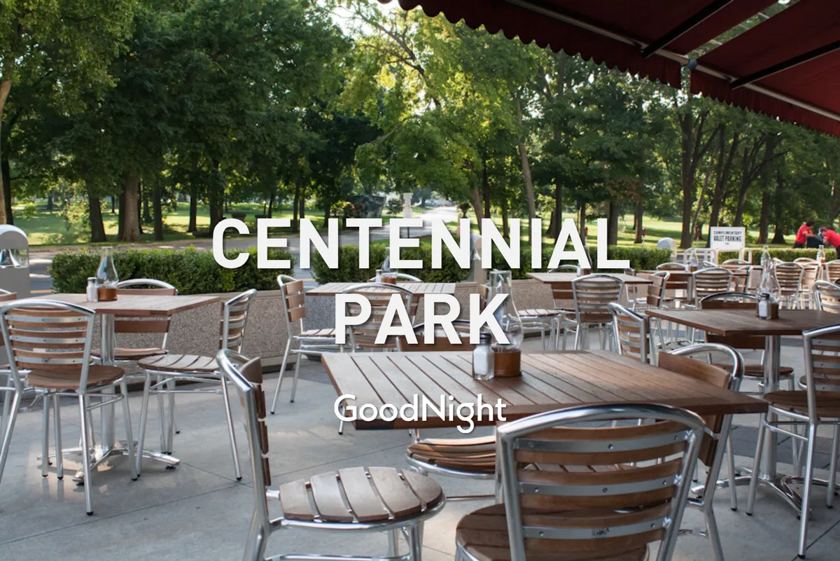 The image showcases outdoor seating with tables surrounded by greenery, suggesting a relaxed setting for picnics or outdoor family gatherings. The atmosphere is peaceful yet social, inviting guests to enjoy fresh air and communal moments.